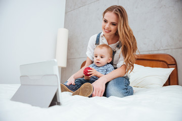 Woman sitting with her son and watching cartoons on tablet