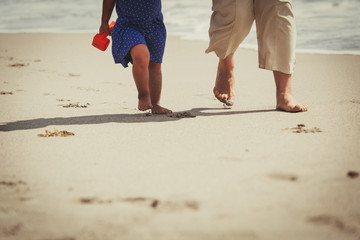 Foot of grandmother with little girl walk at beach