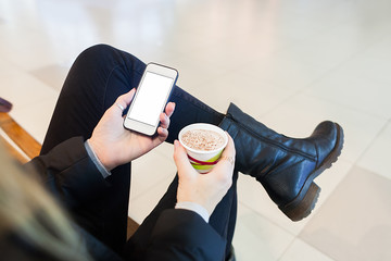 Woman's hands holding smartphone and cup of cappuccino - Powered by Adobe