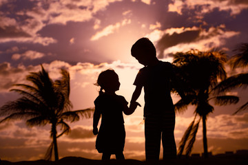 little boy and girl holding hands at sunset beach