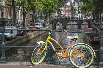 Fototapeta na wymiar Yellow and green bike with old bridge and several buildings in Amsterdam