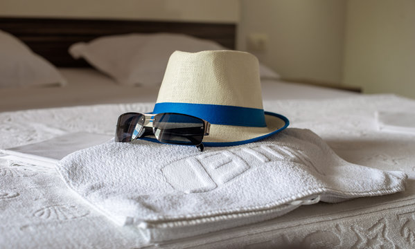 hat, towel and sunglasses on the bed in the hotel 