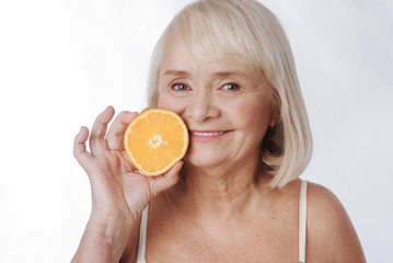 Pleasant content woman holding an orange half