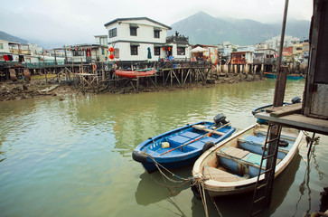 Riverboats in dirty river of old fishermen village Tai O with rustic houses
