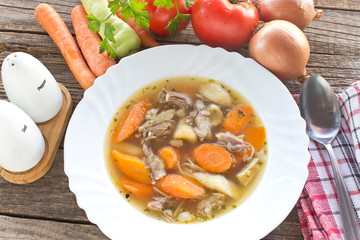 Beef and vegetable soup in plate on wooden table