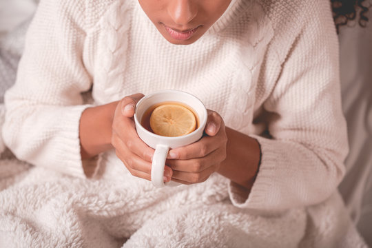 Woman wearing a white sweater and holding a mug of tea