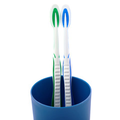 Pair of toothbrushes in blue plastic cup isolated over white background