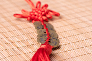 Chinese New Year decoration: Close-up of decorative Chinese lucky coins with knot on bamboo mat,...