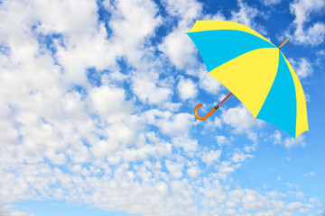 Umbrella in Ukrainian flag colors flies in sky against of pure white clouds.Wind of change concept.