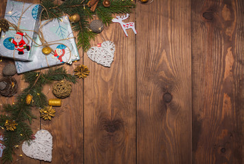 Christmas presents in gift boxes at brown wooden table. Flat lay with copy space Christmas decorations and objects Christmas fir tree branches, hearts, cones. garland Free space