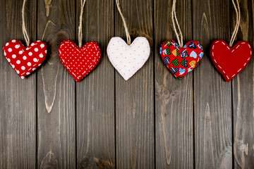five red and white hearts lie on a wooden surface