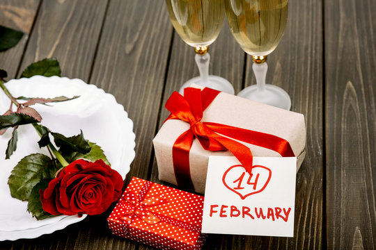 Card with lettering '14 february' lies on present box before pla