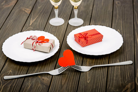 two white plates with gift boxes lie on wooden surface