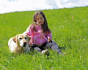 young girl smiling on the grass in the mountains with her labrad