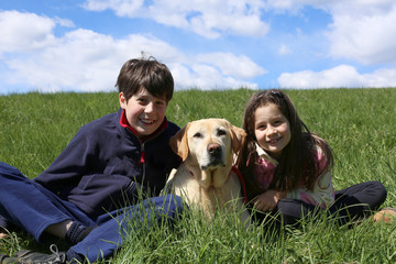 young brothers with their Labrador Retriever dog on a sunny day