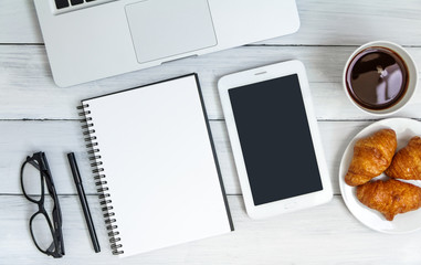 White office desk with laptop, smartphone, notebook on wooden table. Top view with copy space. Student or business accessories flatlay. Office supplies and gadgets on background. View from above.