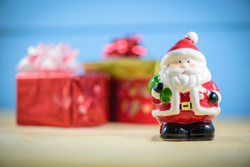 Santa Claus dolls and  blurred Christmas decorations box on wooden table