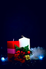 Red and white candles with garland and tinsel at black background