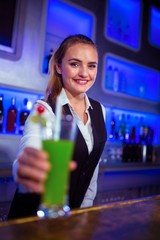 Portrait of smiling bartender serving cocktail