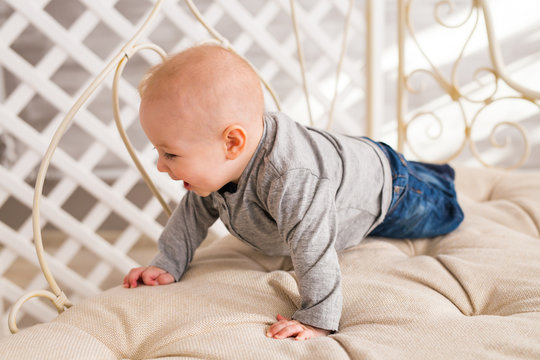 Adorable laughing baby boy in white sunny bedroom. Newborn child relaxing. Family morning at home.