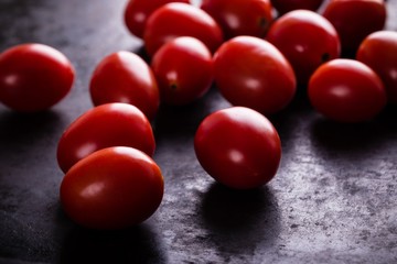 Several red cherry tomatoes on black board