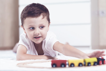 Naklejka premium Adorable little boy playing with toys lying on the floor at the