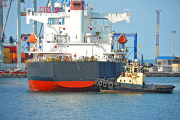 Fototapeta na wymiar Tugboat assisting bulk cargo ship