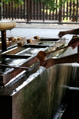 A man washing his hands with a traditional wooden ladle before entering the temple © emmepiphoto