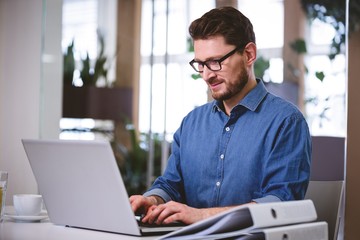 Confident businessman working on laptop at creative office