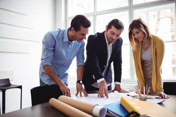 Businessman with coworkers looking at blueprint