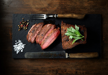 steak grillé sur ardoise noire, couteau et fourchette.
