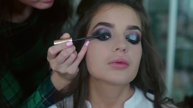 Make up artist applying on mascara on model's eyes slow motion