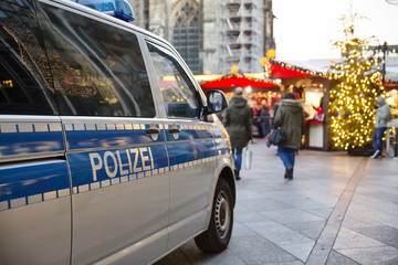 Einsatzwagen der Polizei parkt vor einem weihnachtsmarkt - obrazy, fototapety, plakaty