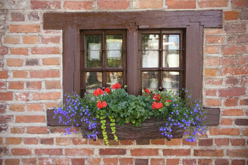 Fototapeta na wymiar Window in an old brick wall With flowers on windowsill