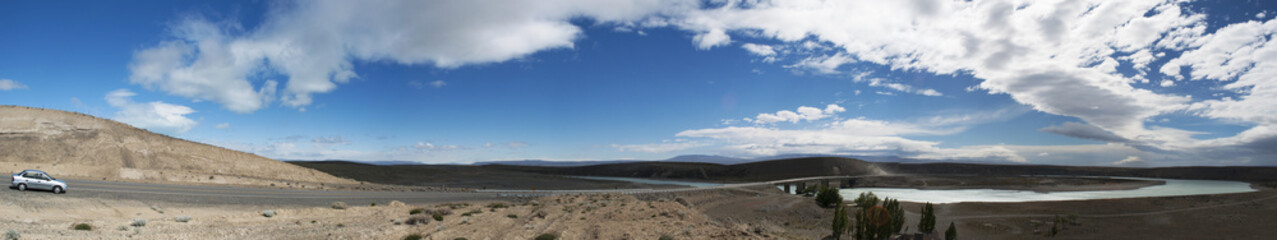 Fototapeta na wymiar Argentina, 21/11/2010: una macchina, una strada e un fiume nel paesaggio sconfinato della Patagonia nei dintorni di El Calafate, la città sul confine meridionale del lago Argentino