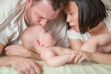 Mixed Race Chinese and Caucasian Baby Boy Laying In Bed with His Father and Mother.