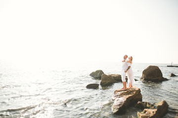Wedding couple kissing and hugging on rocks near blue sea