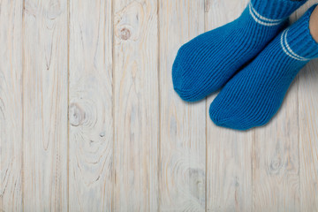 Female feet in knitted blue socks on white wooden background.
