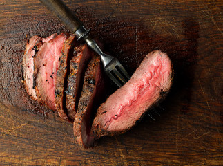 Slices of Medium rare grilled Steak Ribeye on meat fork on white background