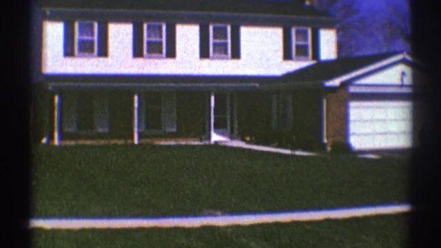 1969: Child Playing Basketball Outside Of A Home, While An Adult Walks Out The Front Door. CLARENDON HILLS ILLINOIS