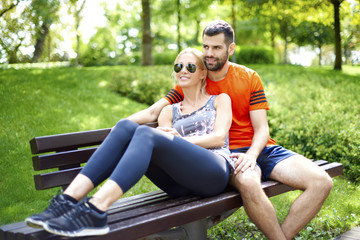 Relaxed sporty couple outdoor. Shot of a sporty young couple relaxing on the bench after running at park