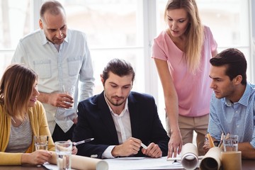 Fototapeta premium Businessman with coworkers looking at blueprint 