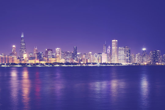 Vintage toned picture of Chicago city skyline with reflection in Lake Michigan at night, USA.