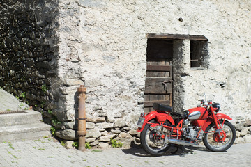 Red Motorcycle on a background of old stone walls and doors. Old
