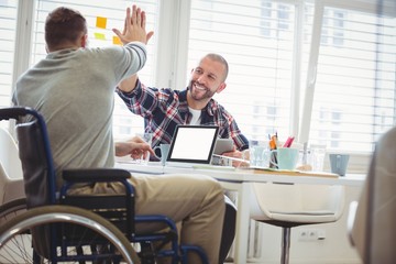 Handicap businessman giving high-five to colleague in office
