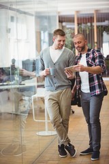 Naklejka premium Full length of businessman showing digital tablet to colleague