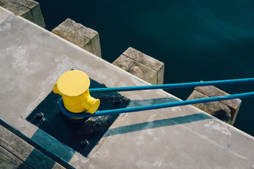 Yellow mooring bollard on pier with mooring rope