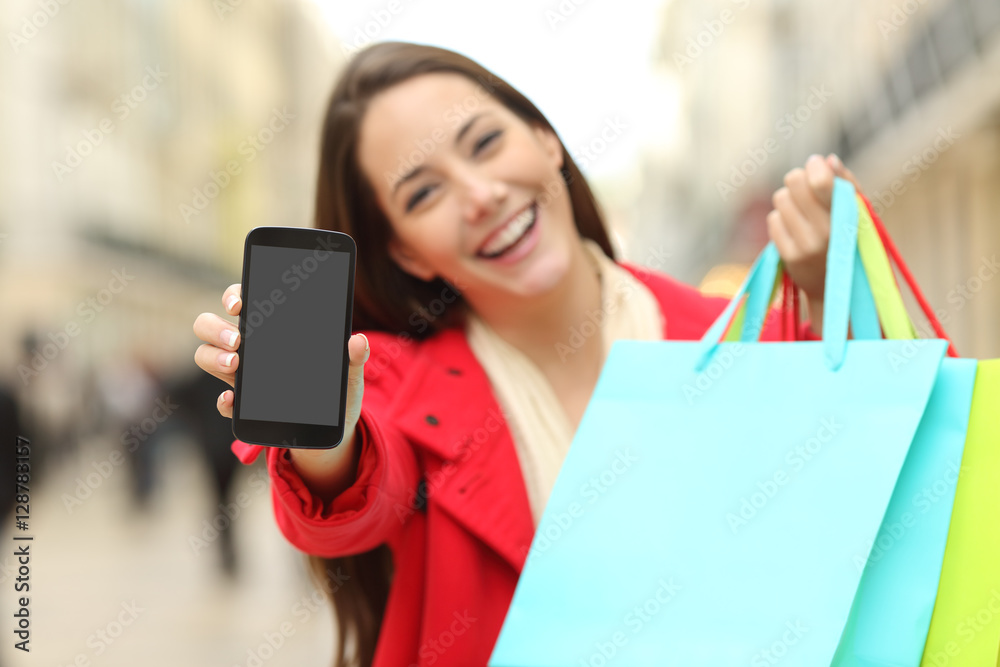 Wall mural Shopper with shopping bags showing phone