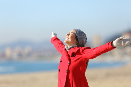 Happy woman breathing raising arms in winter