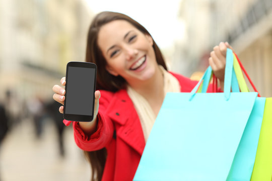 Shopper with shopping bags showing phone